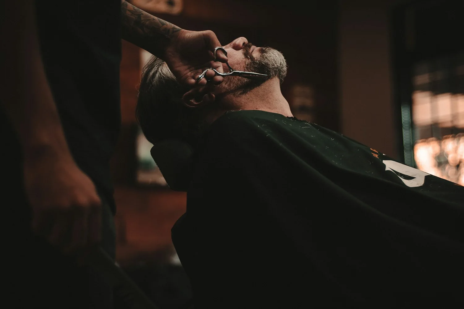 Referência fotográfica de um barbeiro cuidando do acabamento da barba